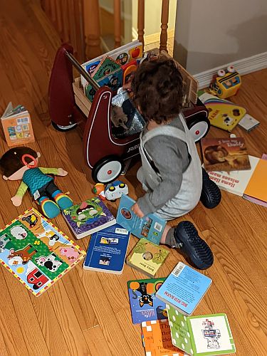 Tom no chão cercado de livros infantis