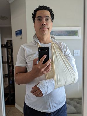 Selfie em frente ao espelho, com o braço engessado numa tipóia